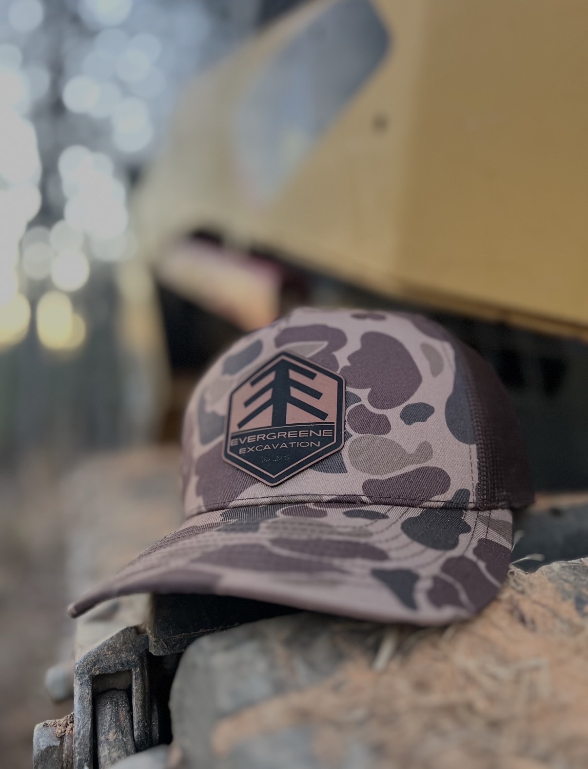 Evergreene Excavation hat resting on excavator equipment at sunset in the woods