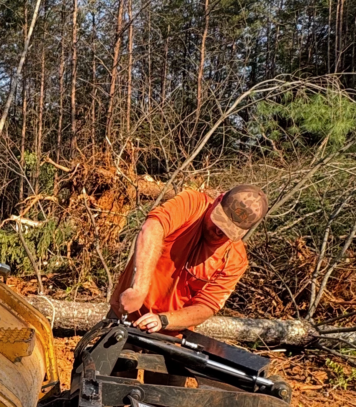 Crew member in the field clearing trees, wearing the Evergreene Excavation hat